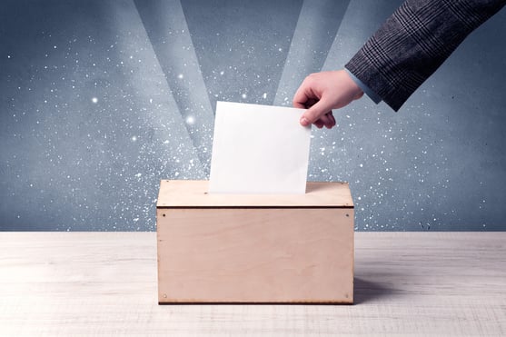 Ballot box with person casting vote on sparkling background