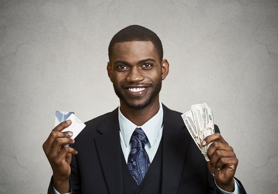 Closeup portrait happy, smiling business man company employee standing, holding dollar bills, credit card hand isolated grey black background. Banking exchange rate concept. Facial expression reaction